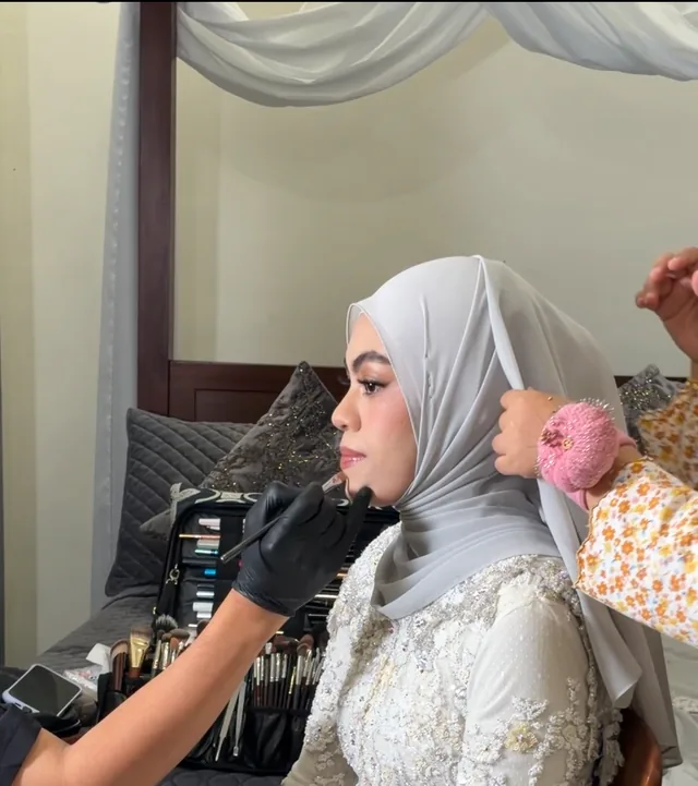 A woman in a white lace dress and headscarf having a pink flower pinned beside her ear
