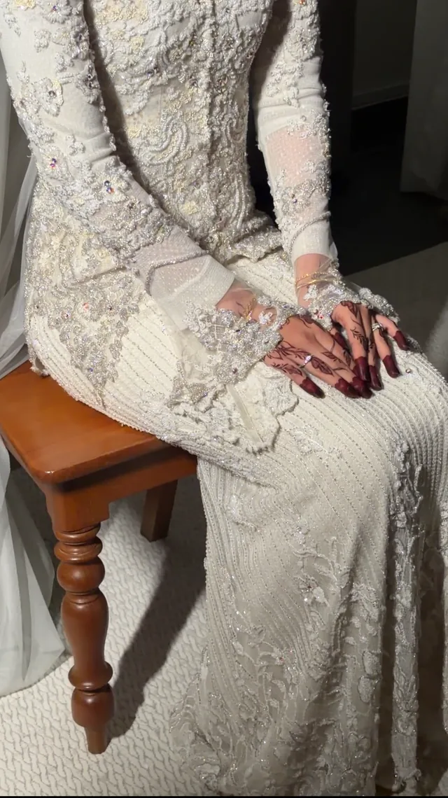 Henna-decorated hands resting on a white beaded dress